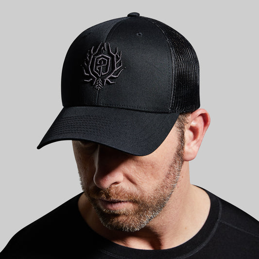 Man wearing a black cap with a logo on a gray background