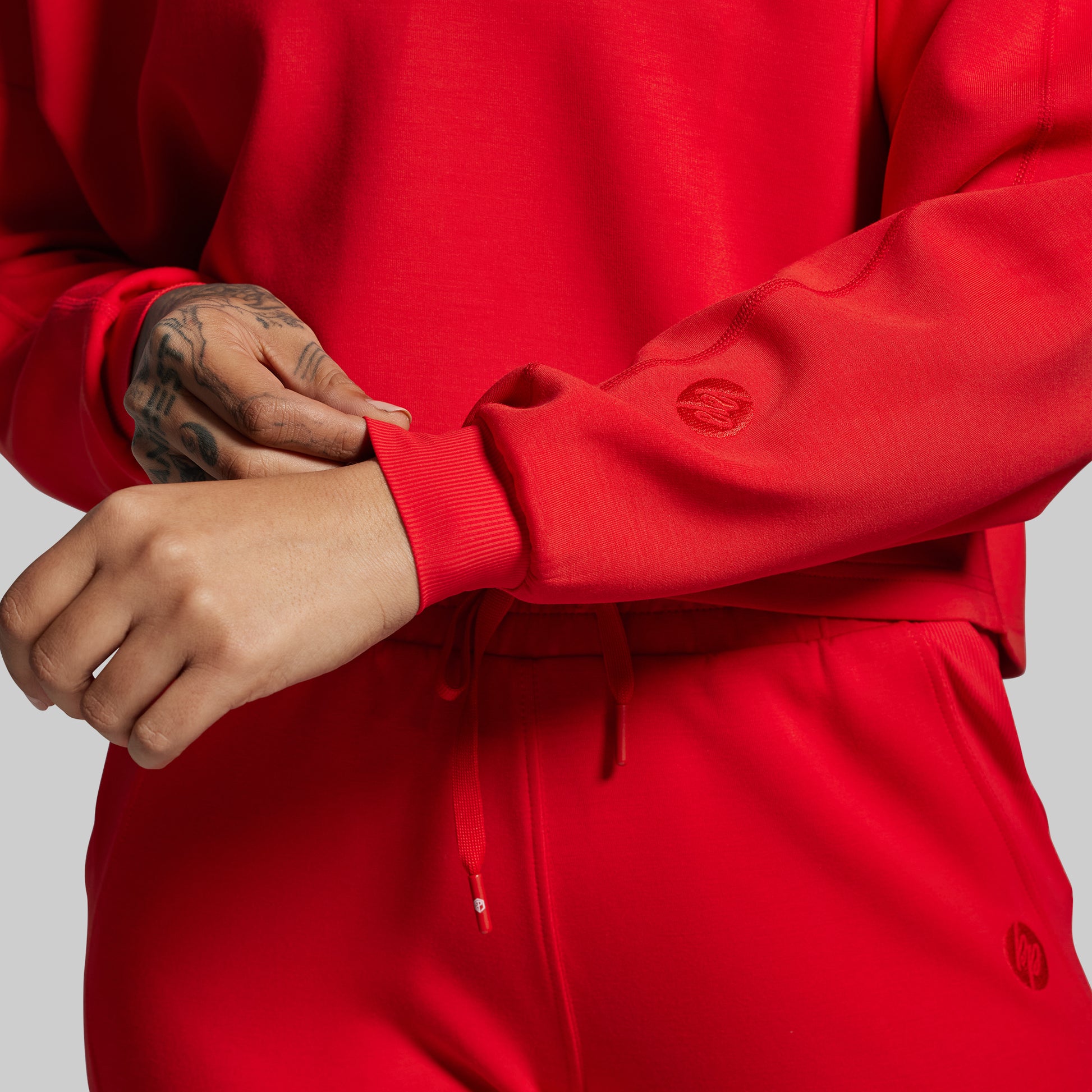 Person wearing a red tracksuit with visible brand logo on a gray background