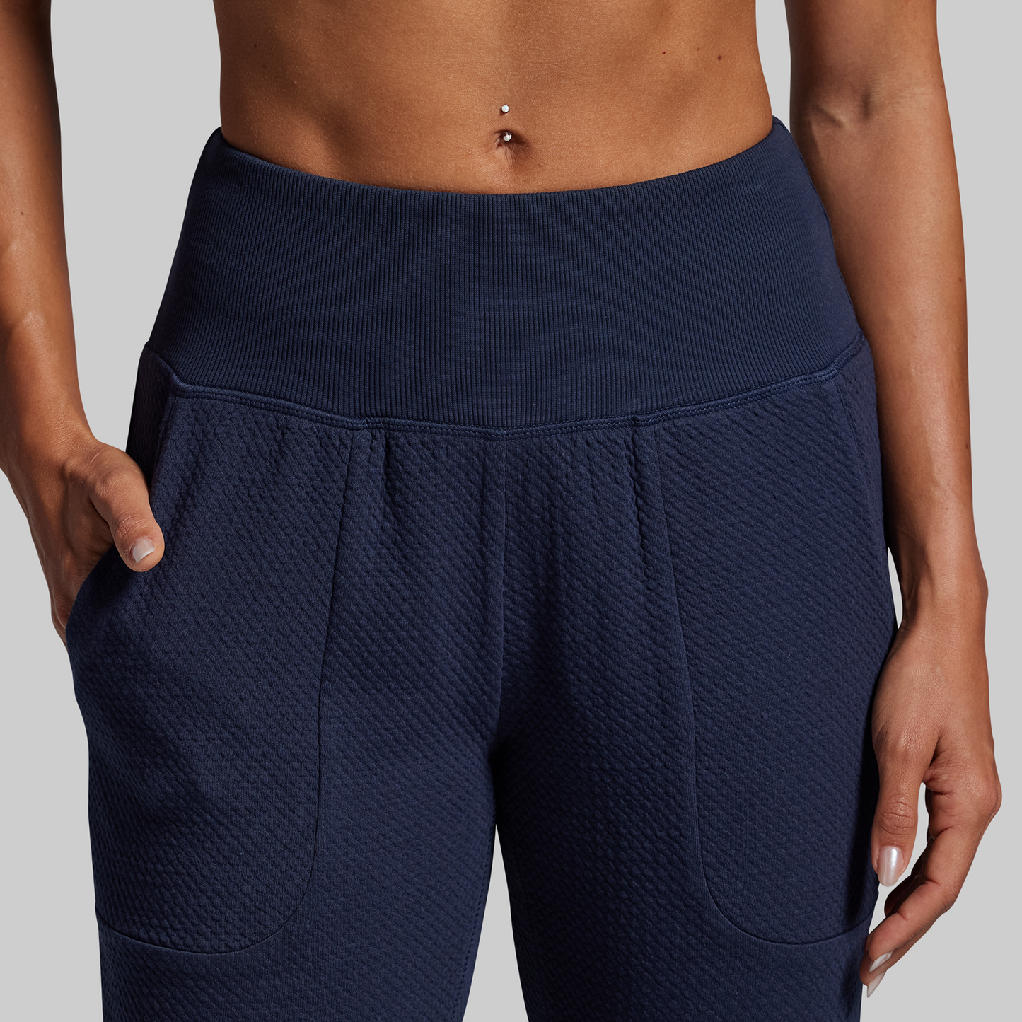 Navy blue textured pants worn by a person on a light gray background