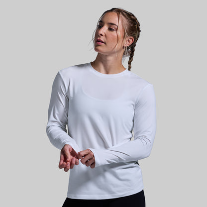 Woman wearing a white long-sleeve shirt against a plain background