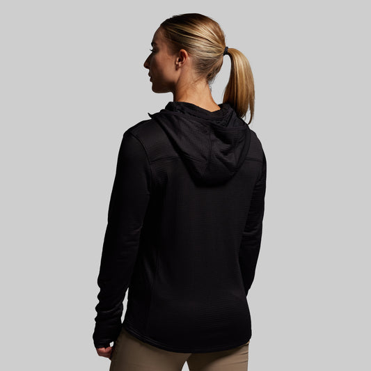 Woman wearing a black hoodie from behind on a gray background