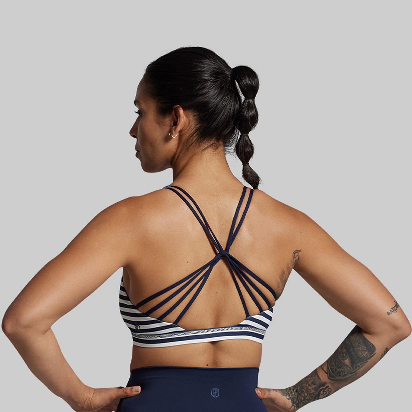 Woman wearing a sports bra and leggings with a gray background