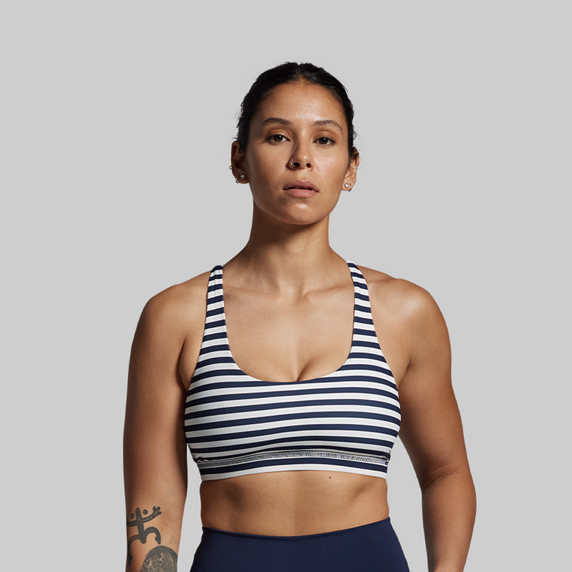 Woman wearing a striped sports bra and leggings on a plain background