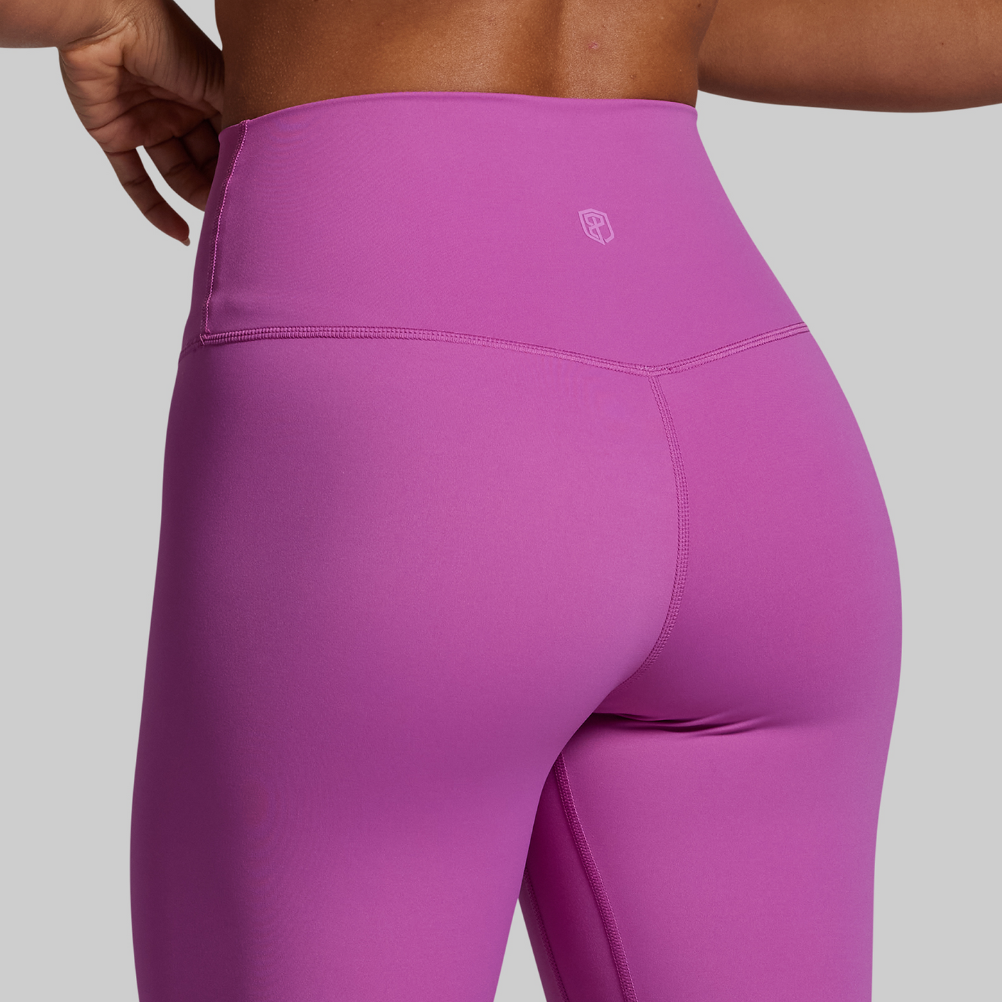 Close-up of purple leggings with a brand logo on a gray background