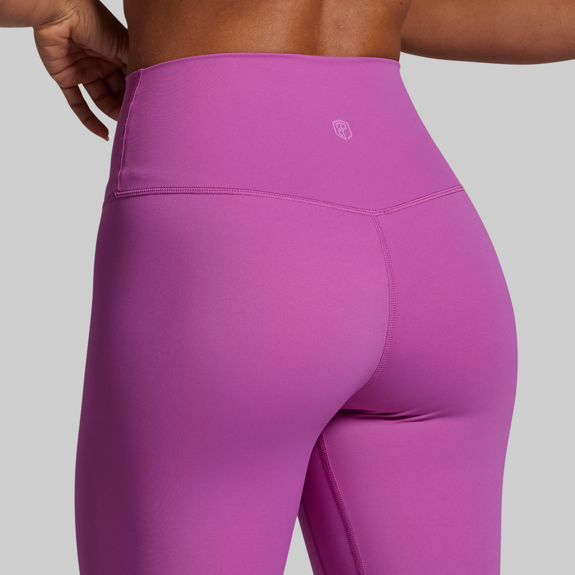 Close-up of purple leggings with a brand logo on a gray background