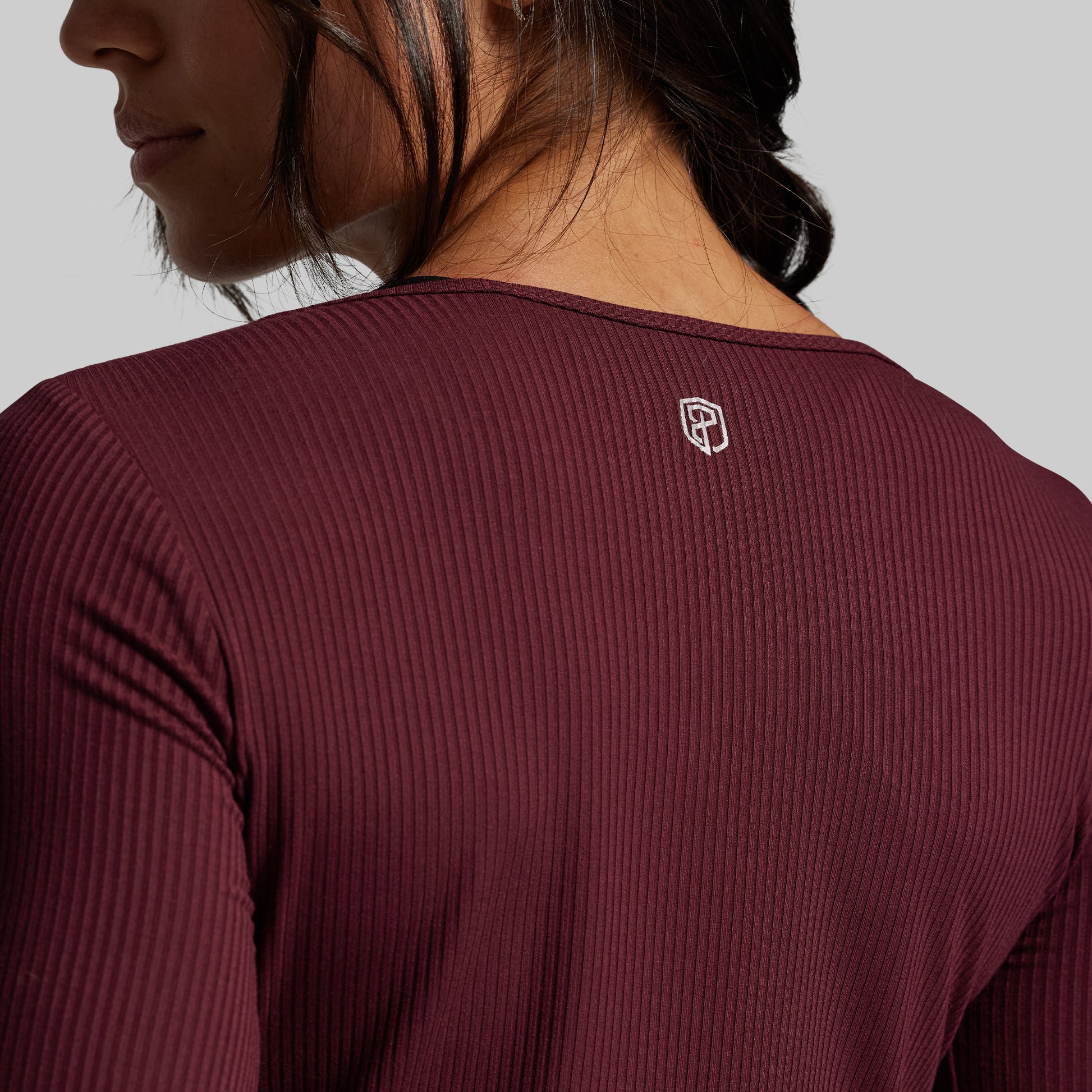 Maroon long-sleeve athletic shirt with a small logo on the chest against a neutral background