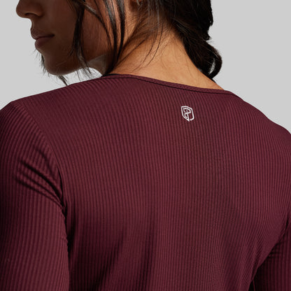 Maroon long-sleeve athletic shirt with a small logo on the chest against a neutral background