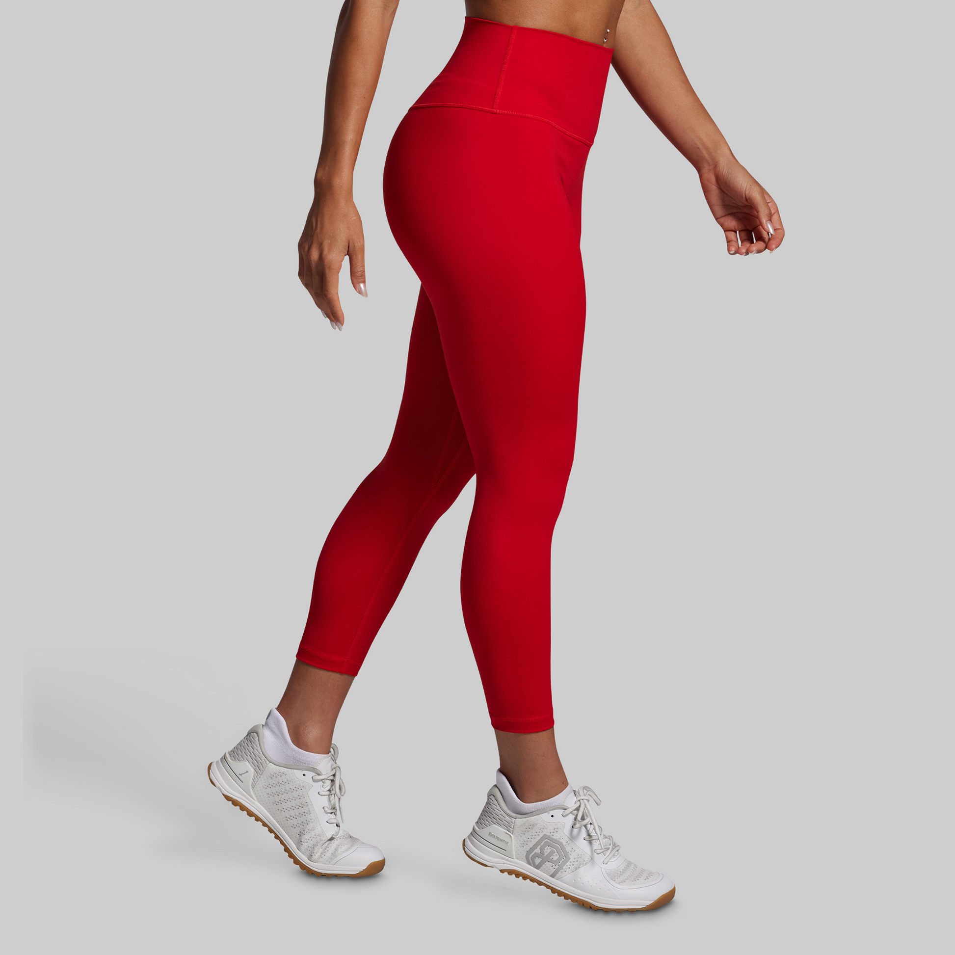Person wearing red leggings and white sneakers on a gray background