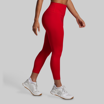 Person wearing red leggings and white sneakers on a gray background