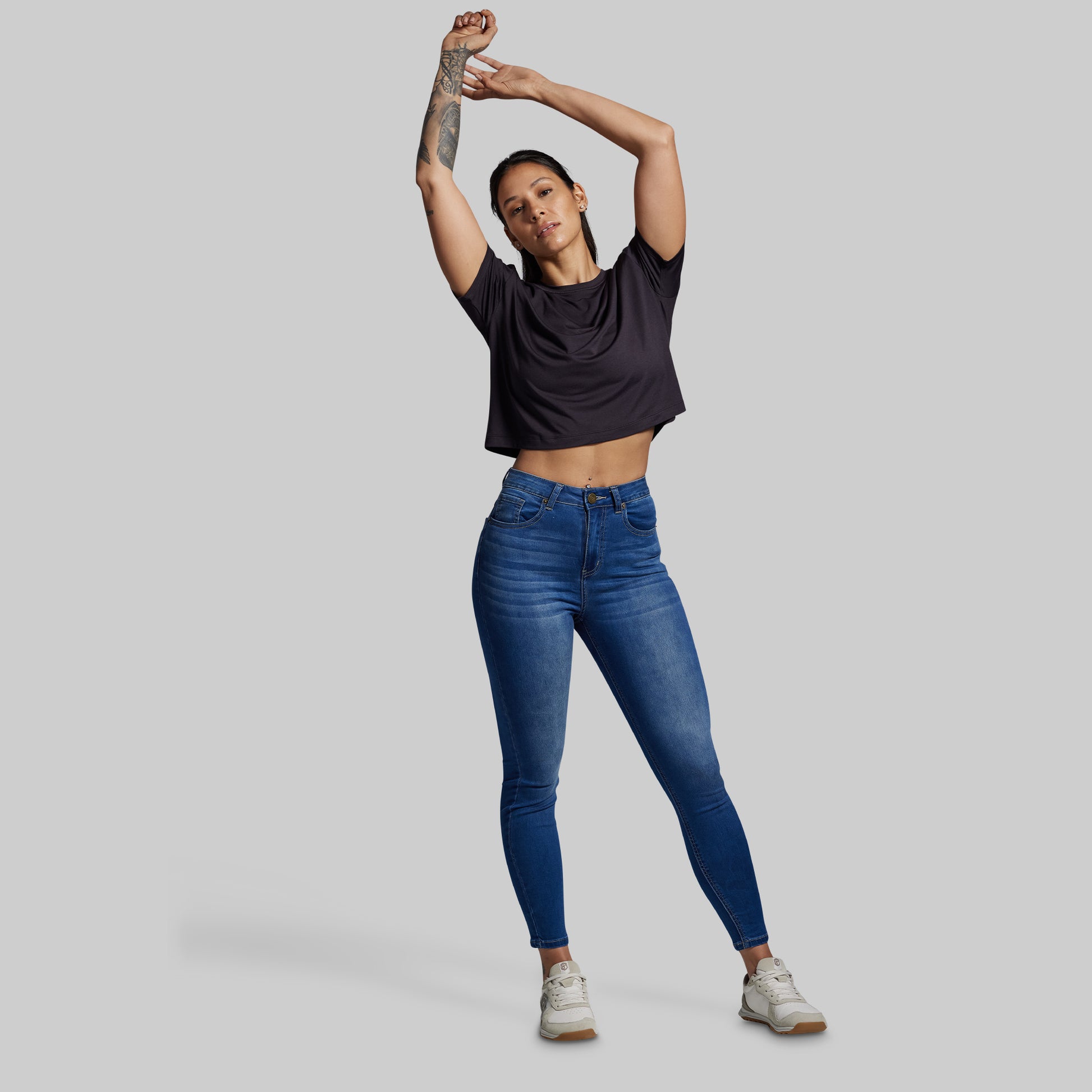 Person wearing a black t-shirt and blue jeans on a gray background