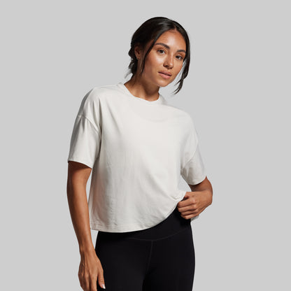 Woman wearing a white t-shirt and black leggings against a gray background