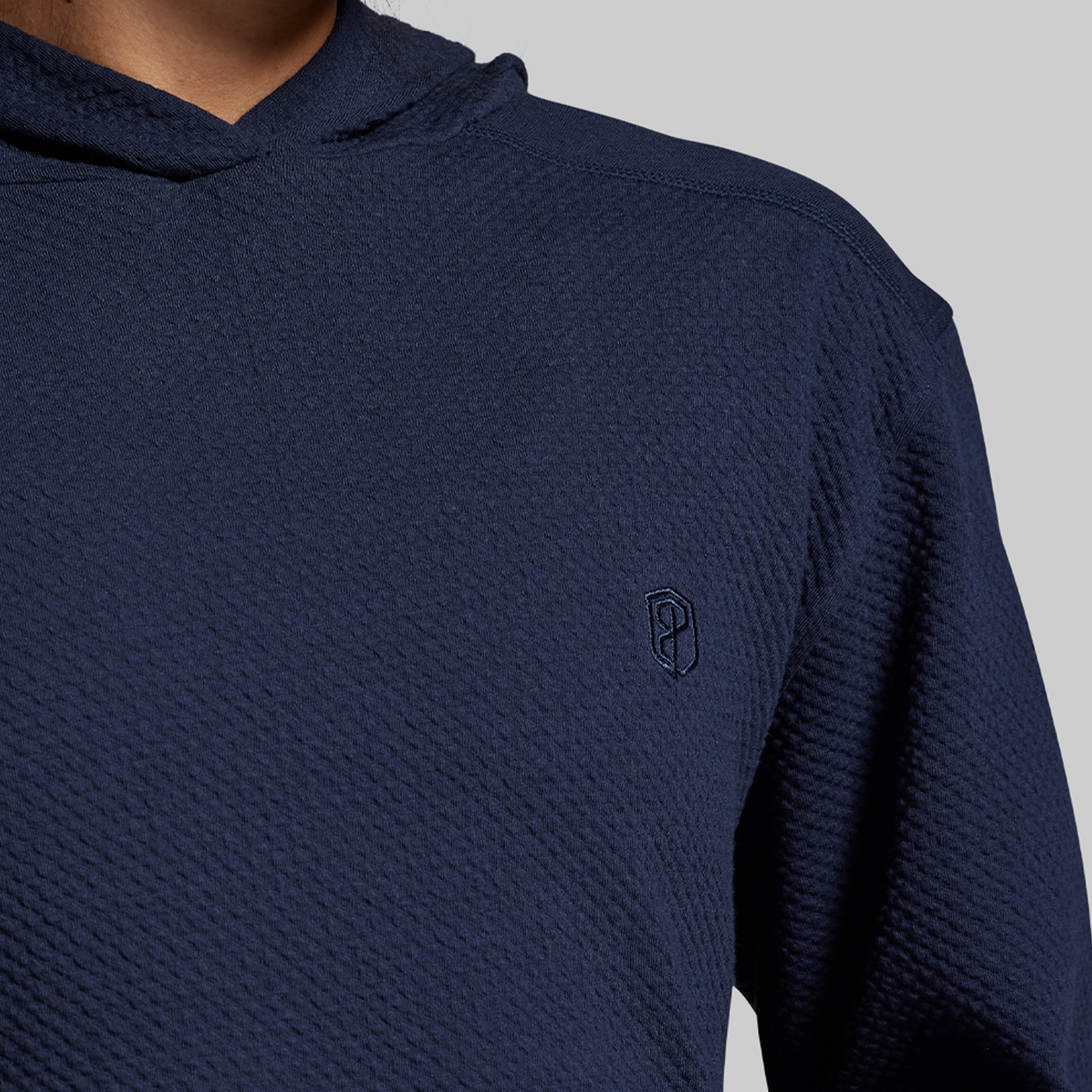 Navy blue textured hoodie with a small logo on a gray background