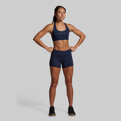 Woman wearing a navy sports bra and shorts set on a gray background