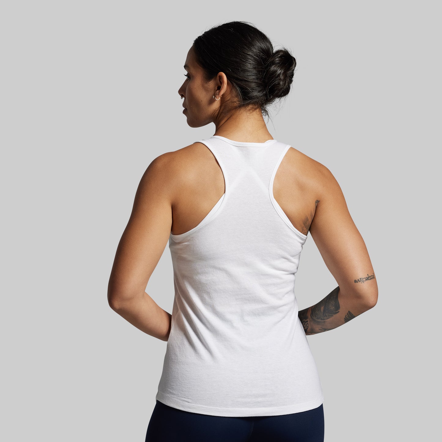 Person wearing a white tank top on a plain background