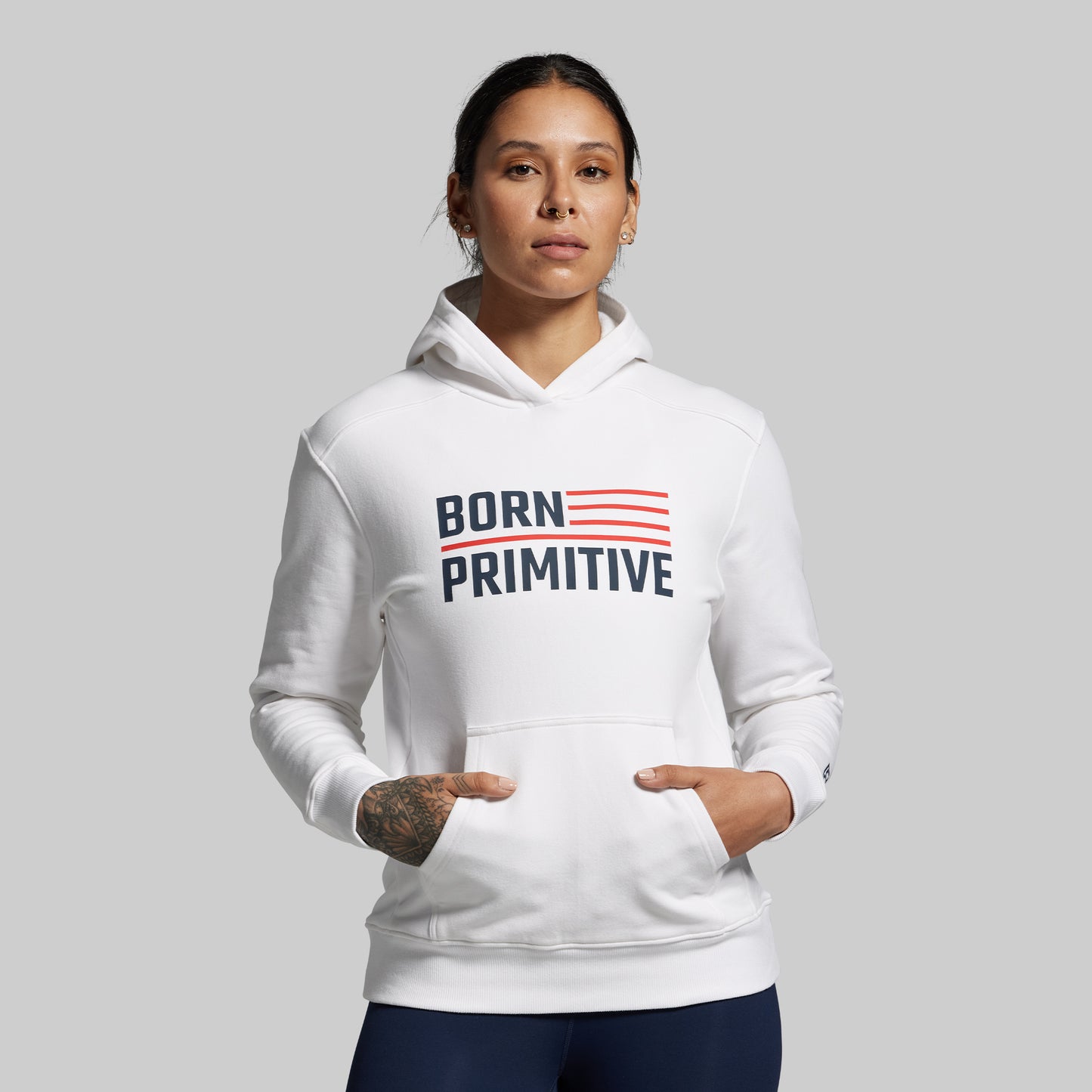 Person wearing a white hoodie with 'Born Primitive' text on a gray background