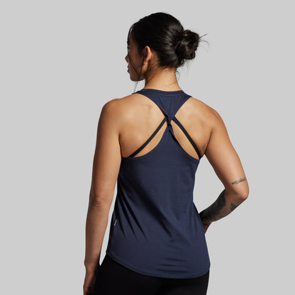 Woman wearing a navy blue tank top with thin straps on a gray background