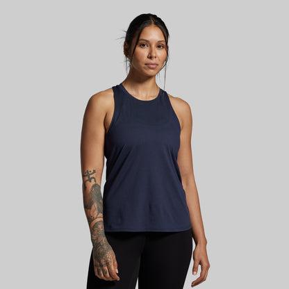 Woman wearing a navy blue tank top against a gray background