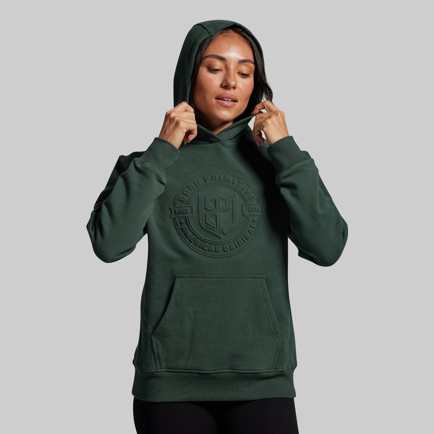 Person wearing a green hoodie with a logo on a gray background