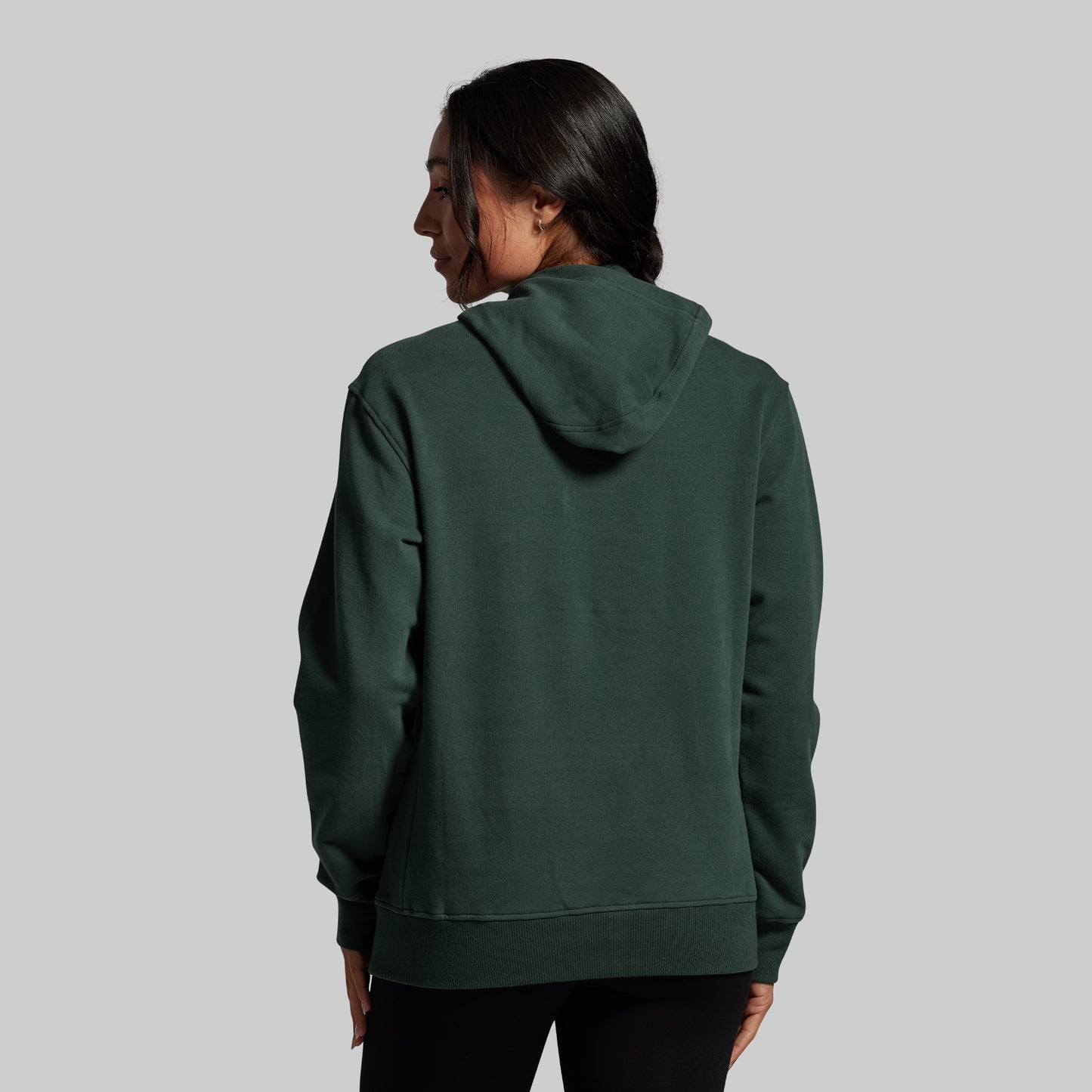 Person wearing a green hoodie from behind on a gray background