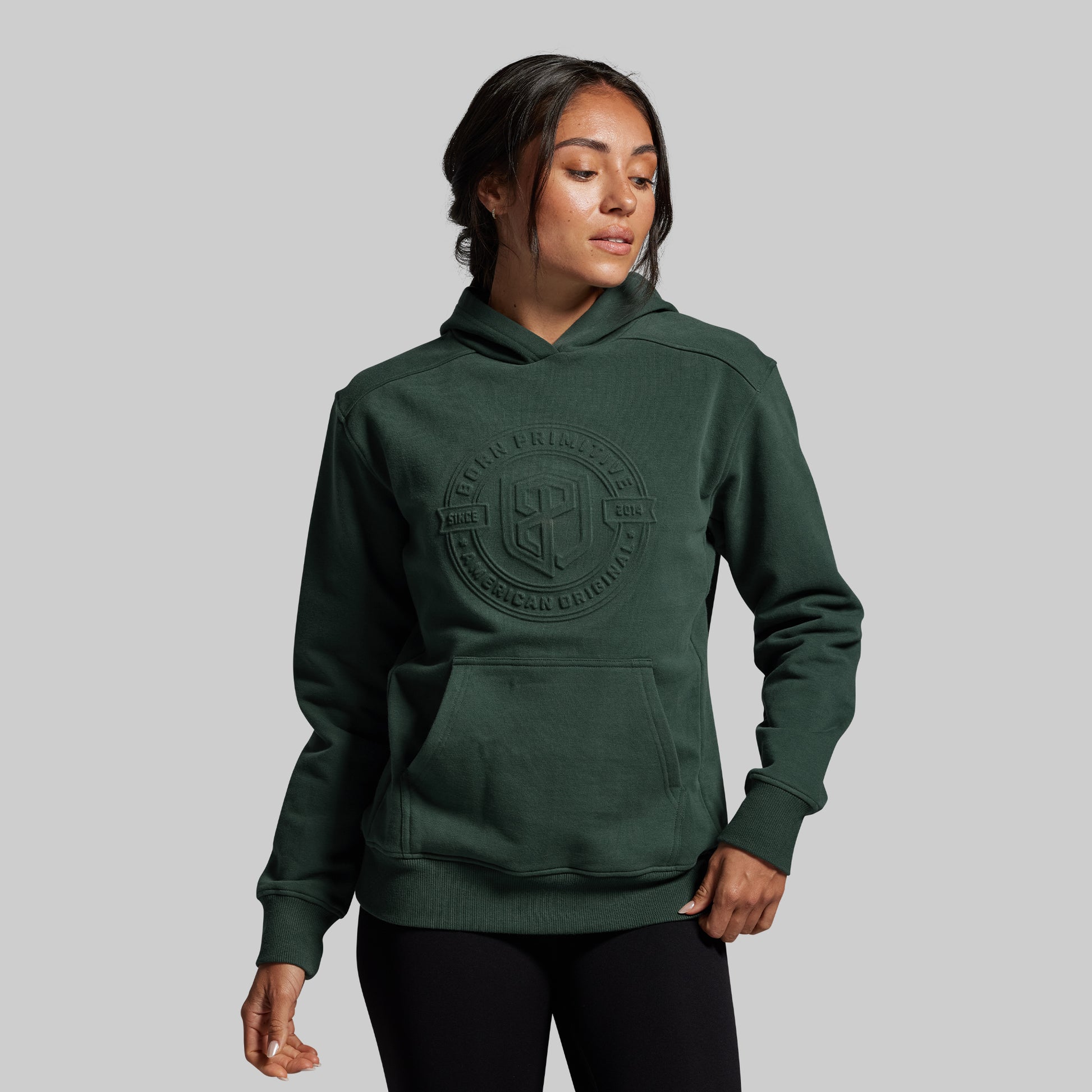 Person wearing a green hoodie with a logo on a gray background