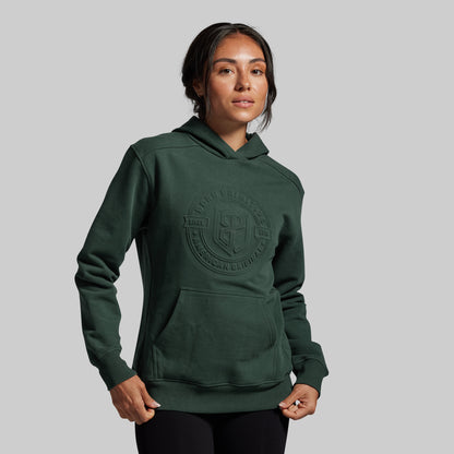 Person wearing a green hoodie with a logo on a gray background