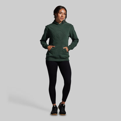 Person wearing a green hoodie and black leggings on a gray background