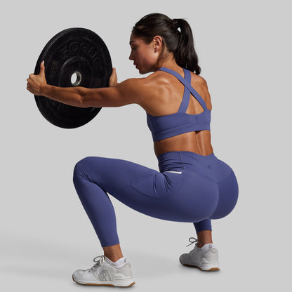 Woman in purple athletic wear lifting a barbell on a gray background