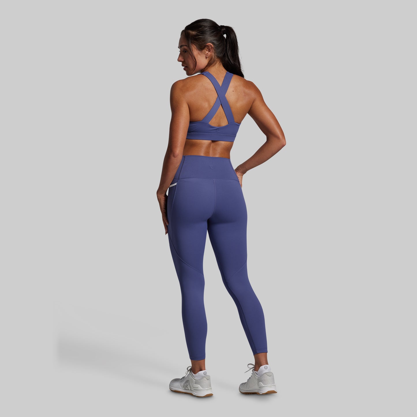 Person wearing a blue sports bra and leggings set on a gray background