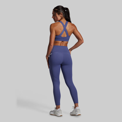 Person wearing a blue sports bra and leggings set on a gray background