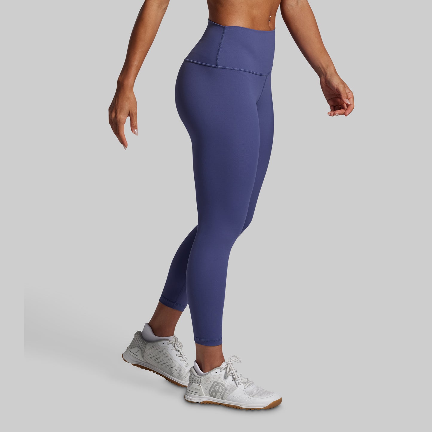 Person wearing blue leggings and white sneakers on a gray background