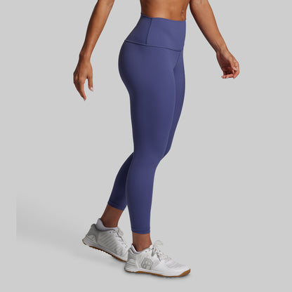 Person wearing blue leggings and white sneakers on a gray background