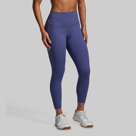 Person wearing blue leggings and white sneakers on a gray background