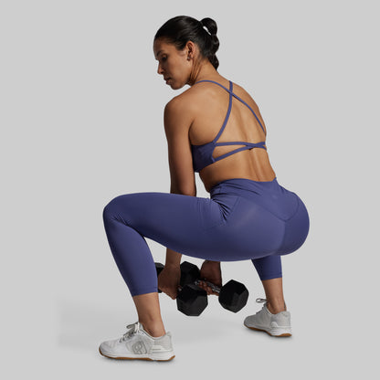 Woman in purple athletic wear lifting weights on a plain background
