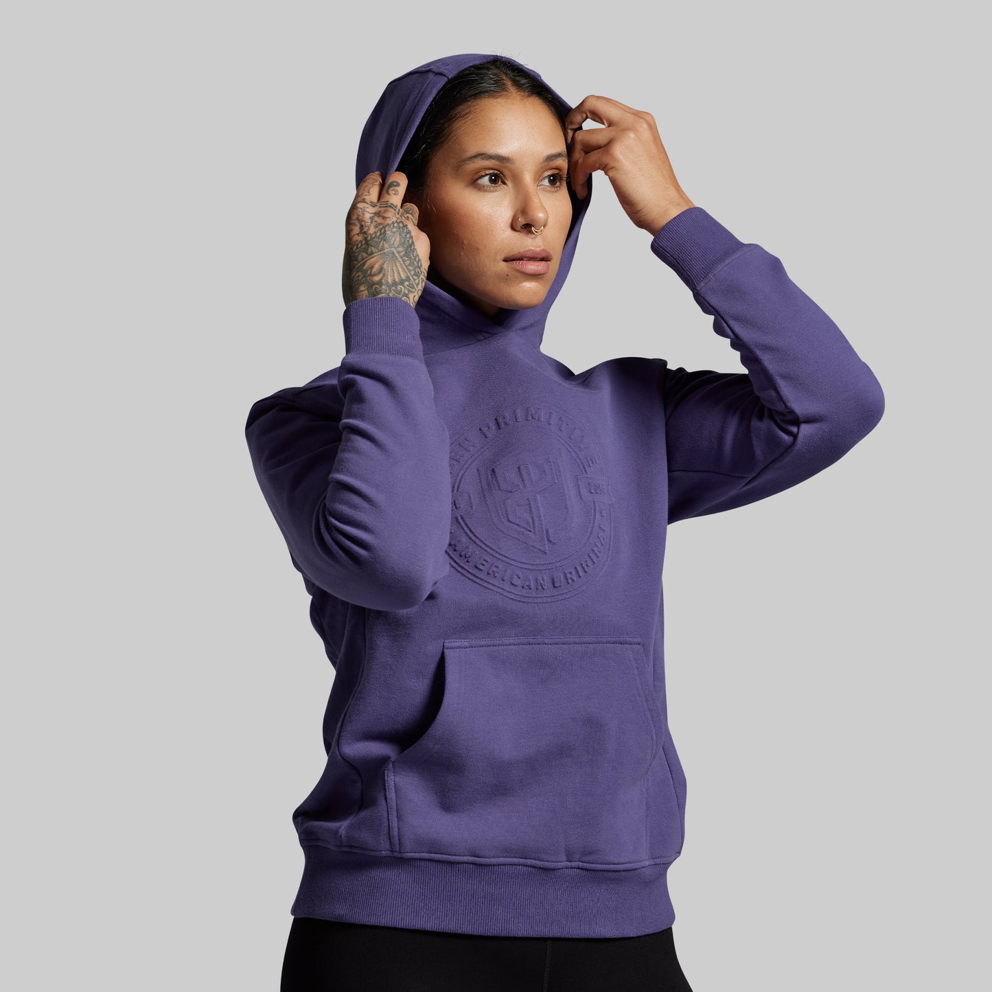 Person wearing a purple hoodie with a logo on a gray background