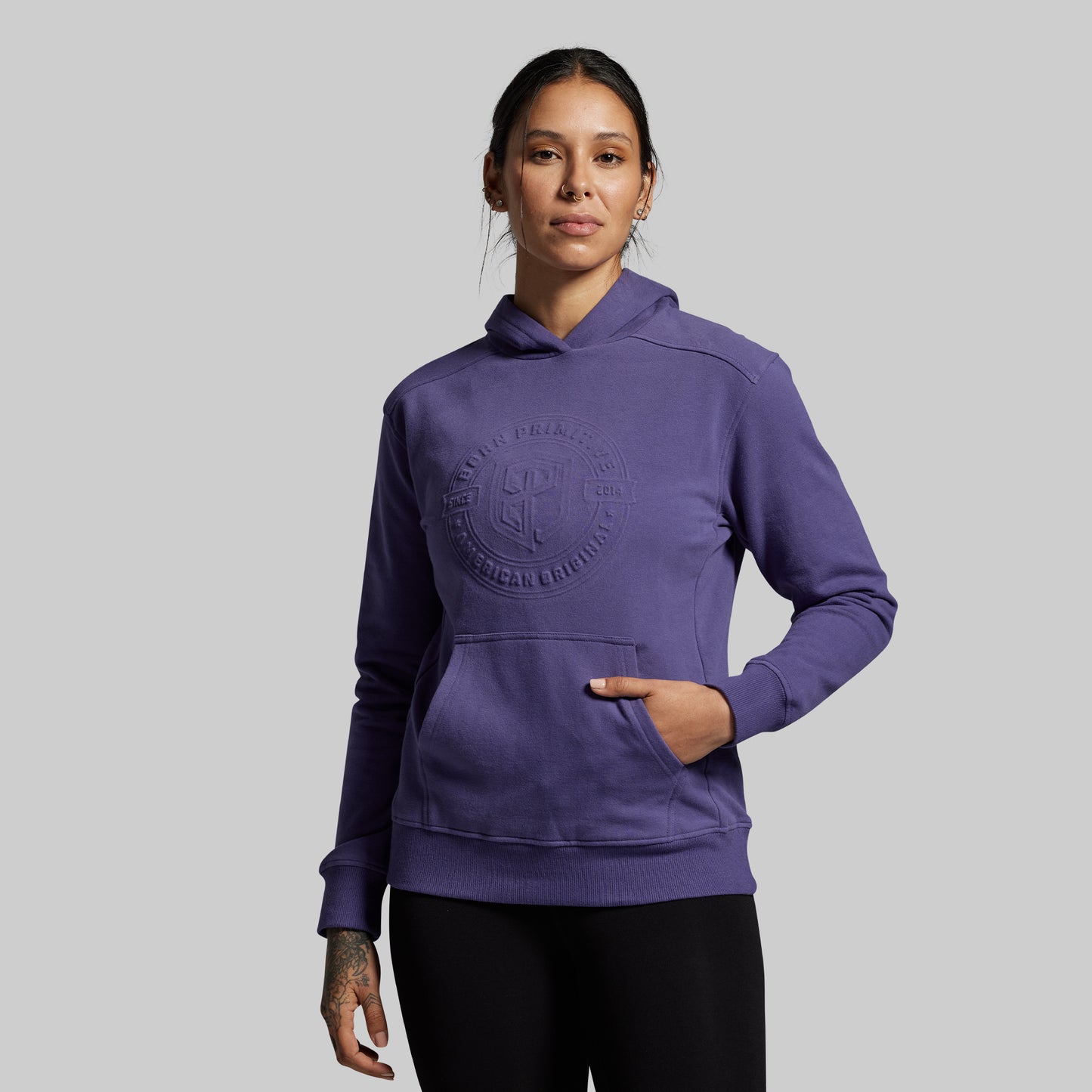 Person wearing a purple hoodie with a logo on a gray background