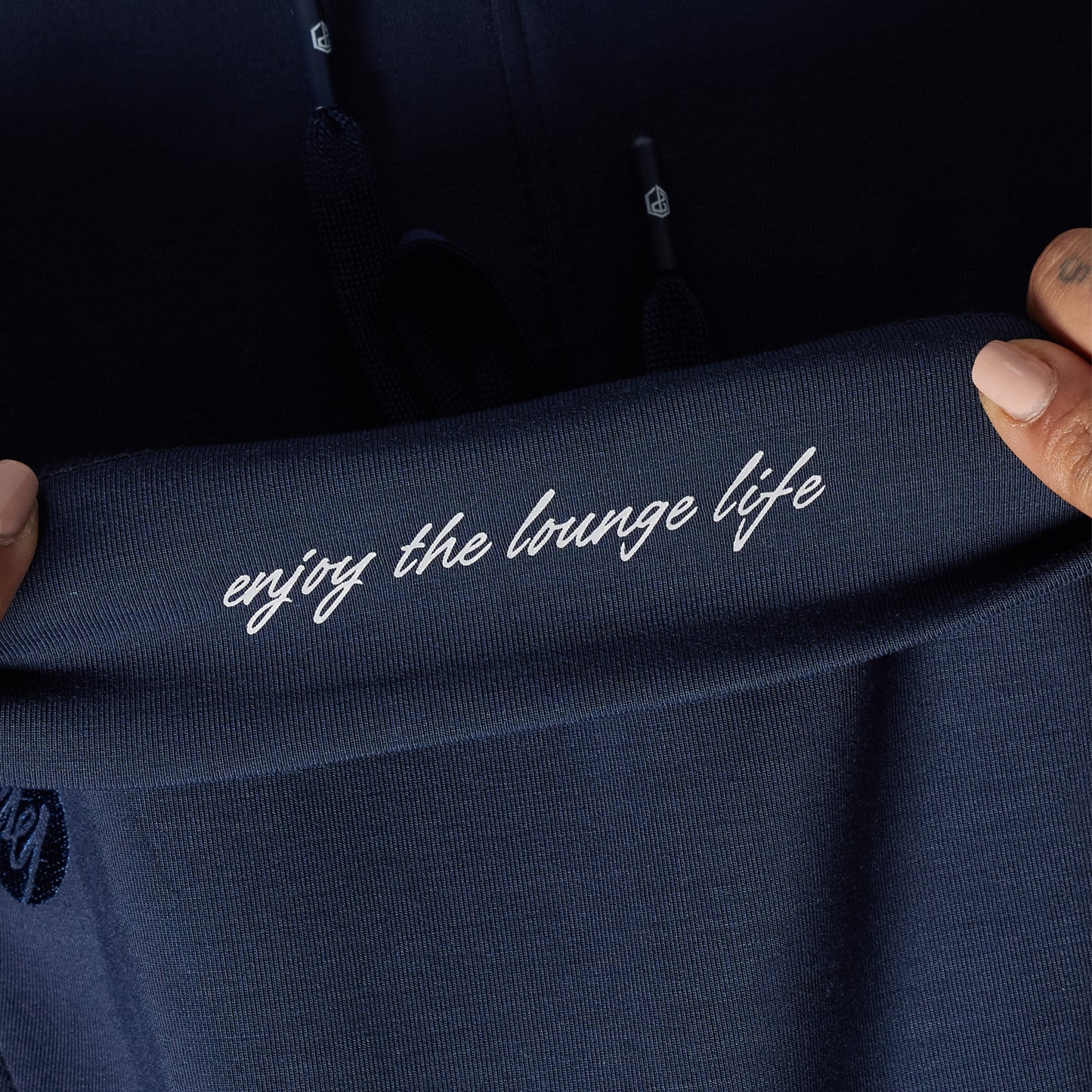 Navy blue garment with 'enjoy the lounge life' text held by a person.