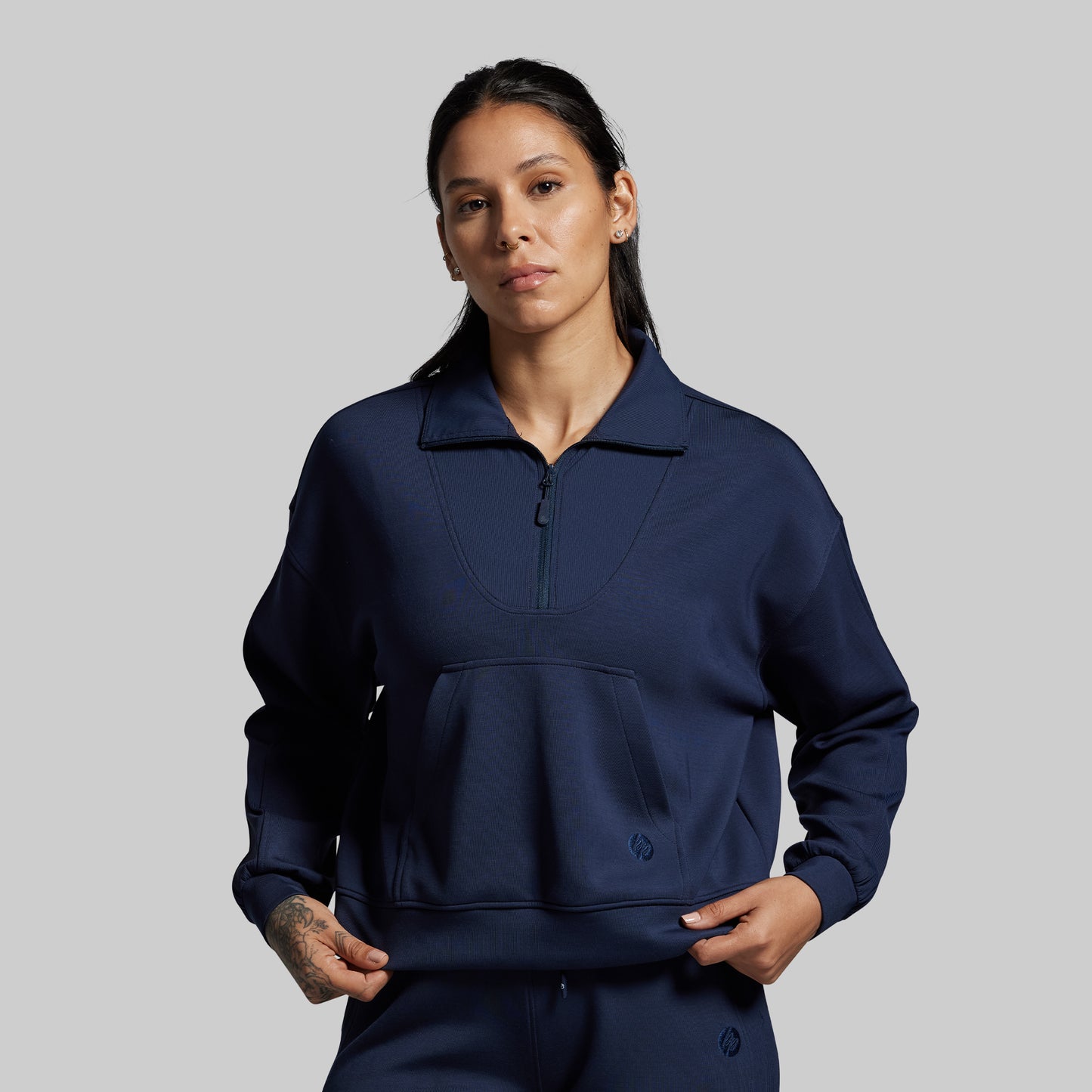 Person wearing a navy blue pullover with a zipper on a gray background