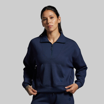 Person wearing a navy blue pullover with a zipper on a gray background