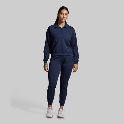 Person wearing a navy blue tracksuit on a gray background