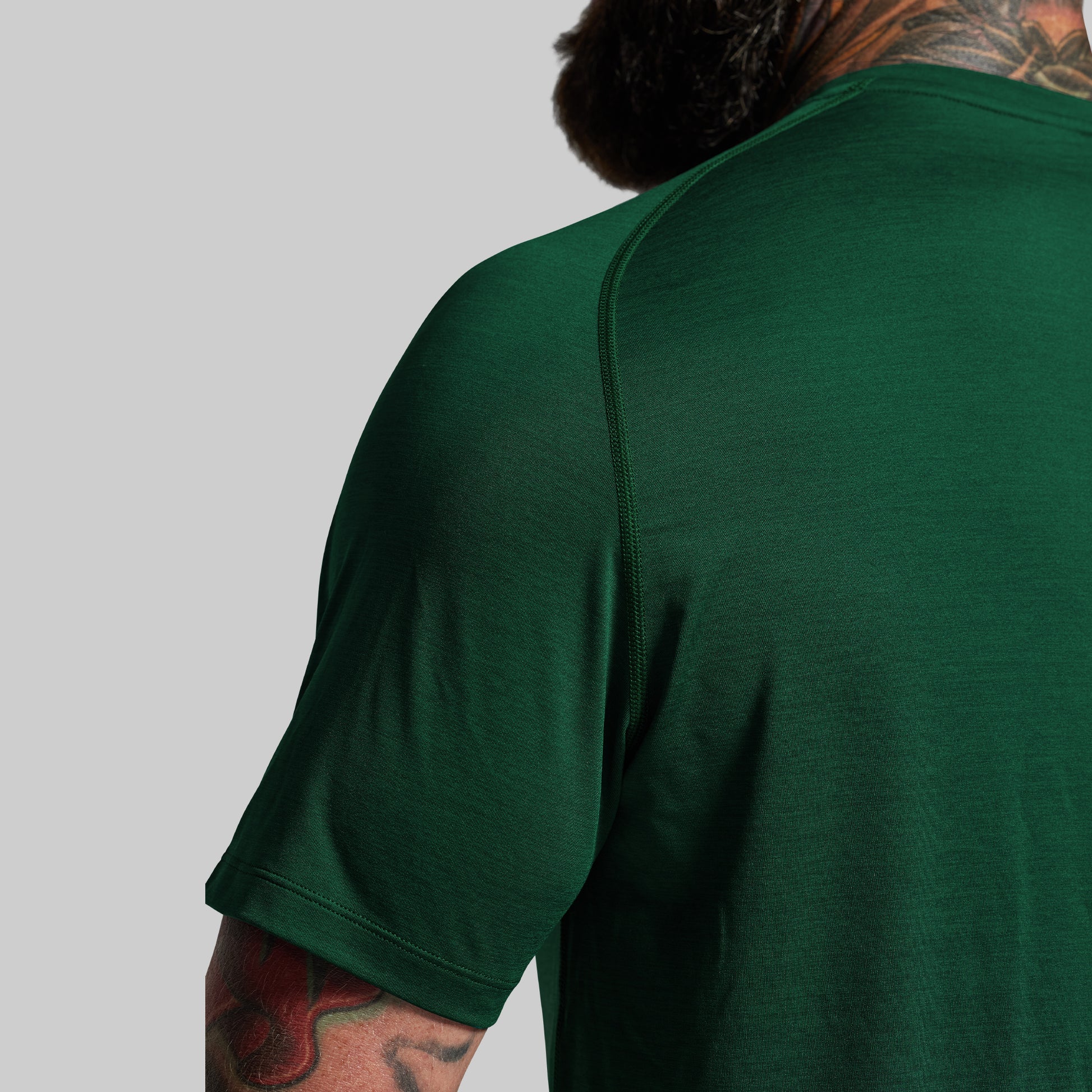 Person wearing a green t-shirt with a plain background
