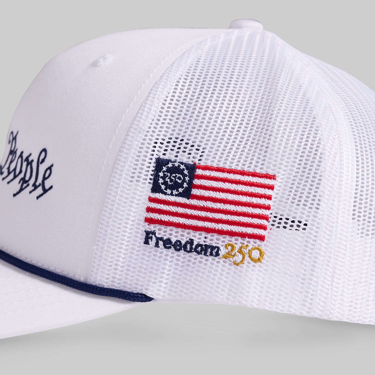 White cap with American flag and 'Freedom 250' text on a gray background
