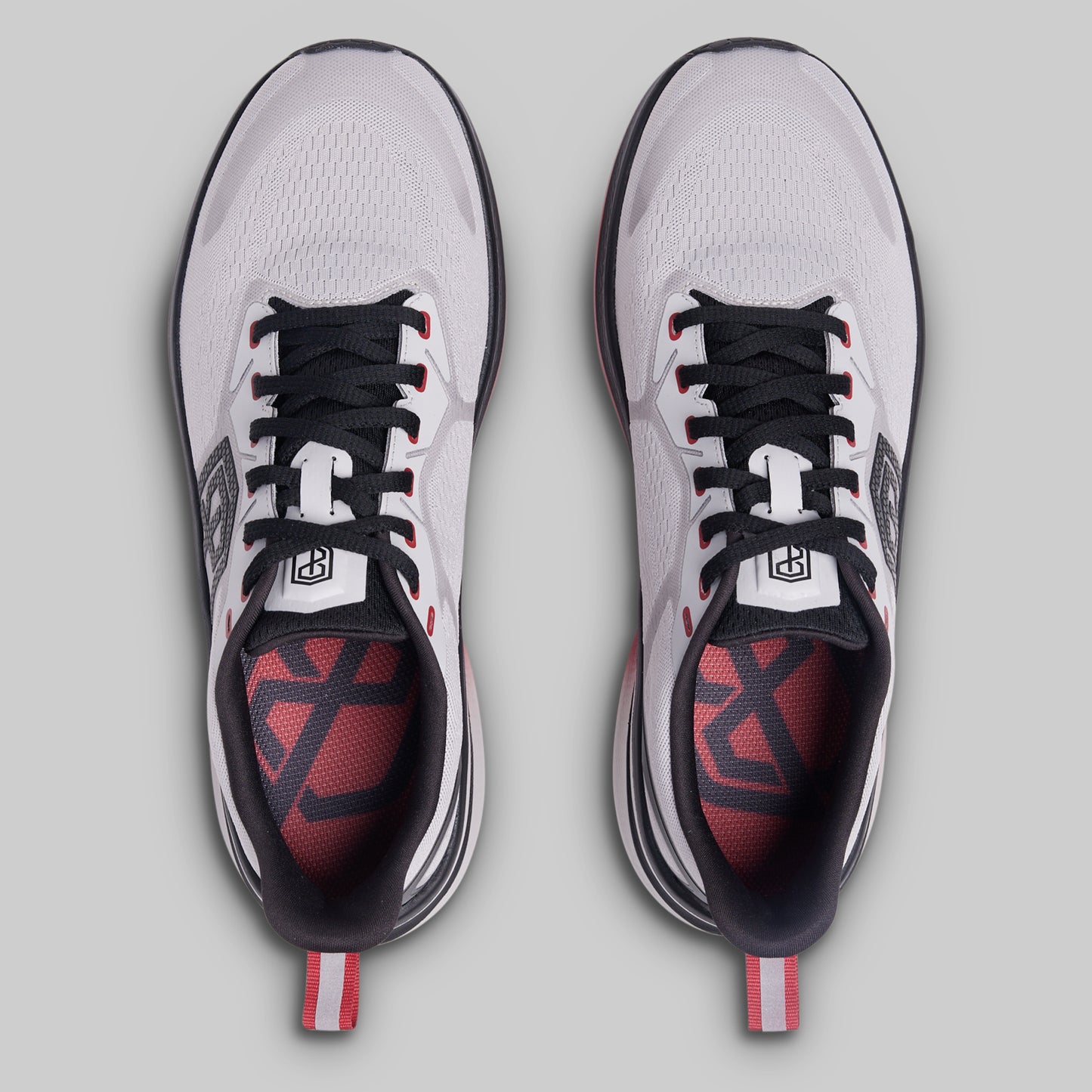 Pair of white athletic shoes with black and red accents on a gray background