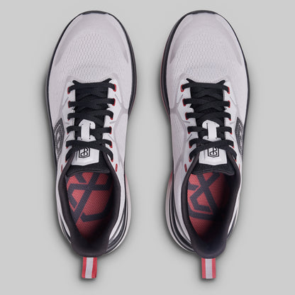 Pair of white athletic shoes with black and red accents on a gray background