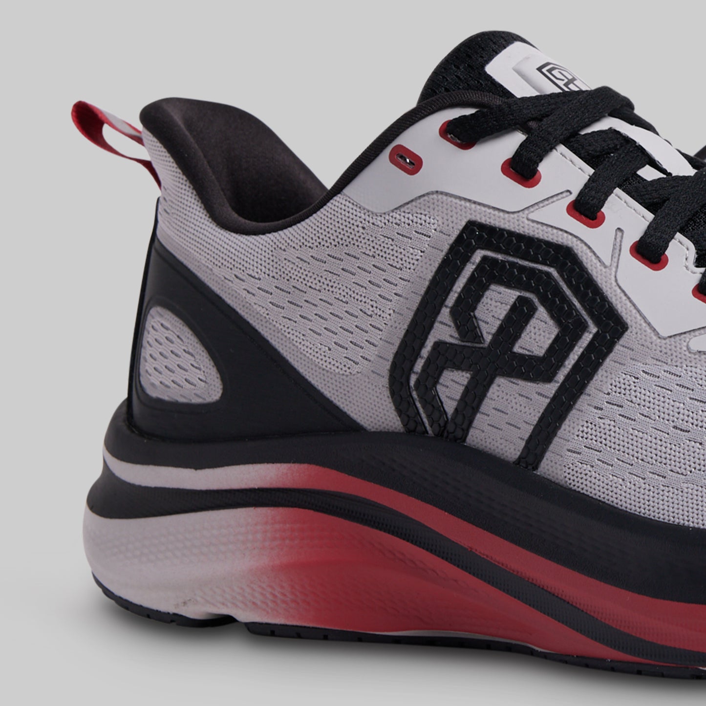 Gray and red athletic shoe with a black logo on a light gray background