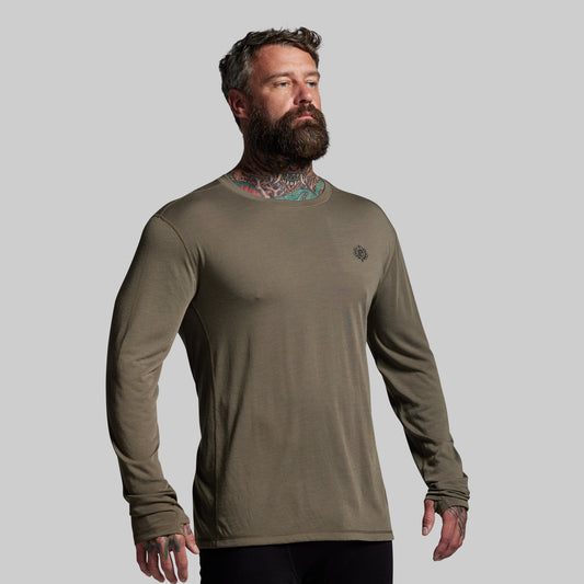 Man wearing a green long-sleeve shirt against a gray background