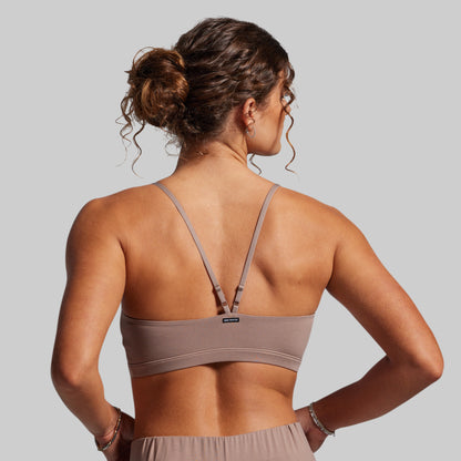 Woman wearing a beige sports bra on a plain background