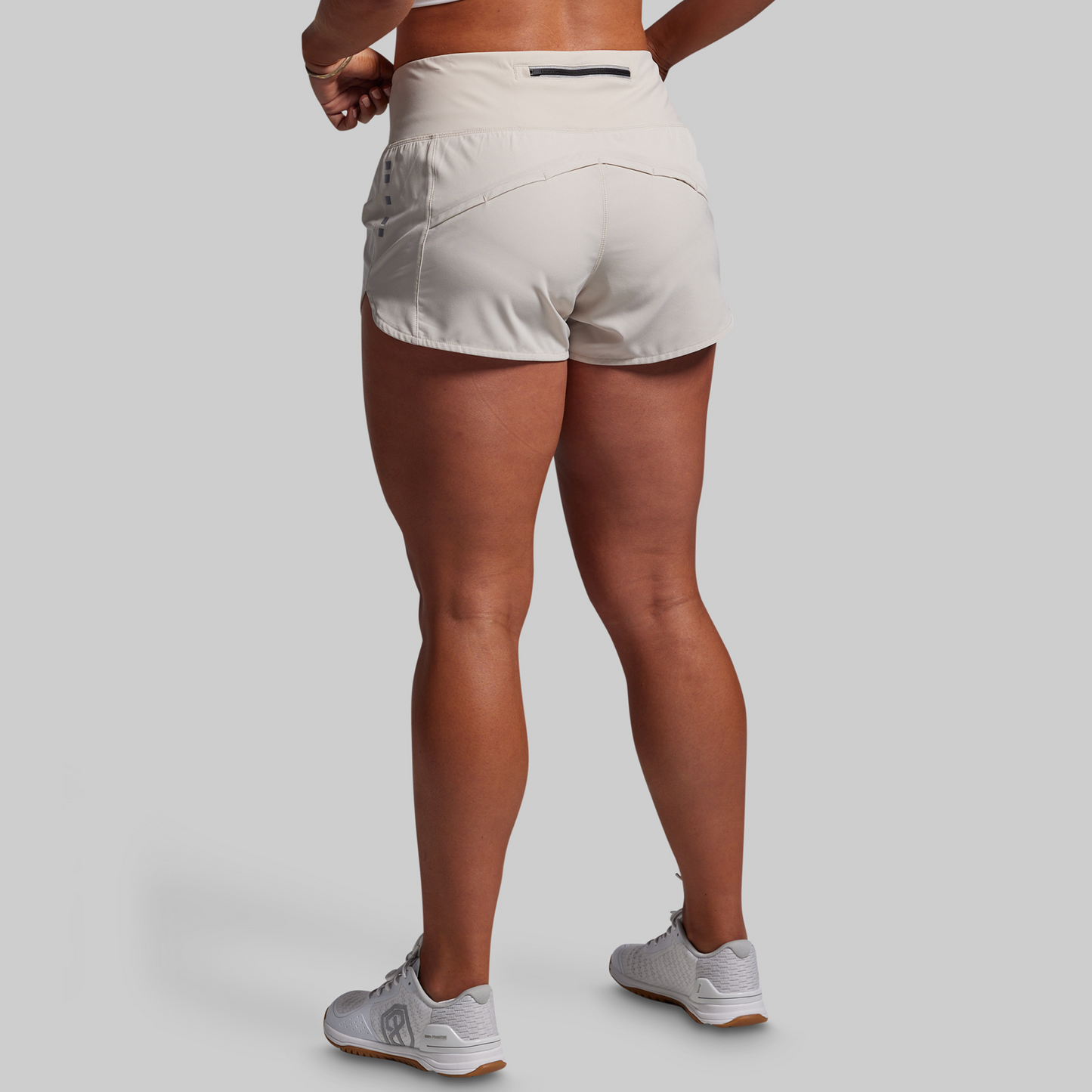Person wearing beige athletic shorts on a plain background