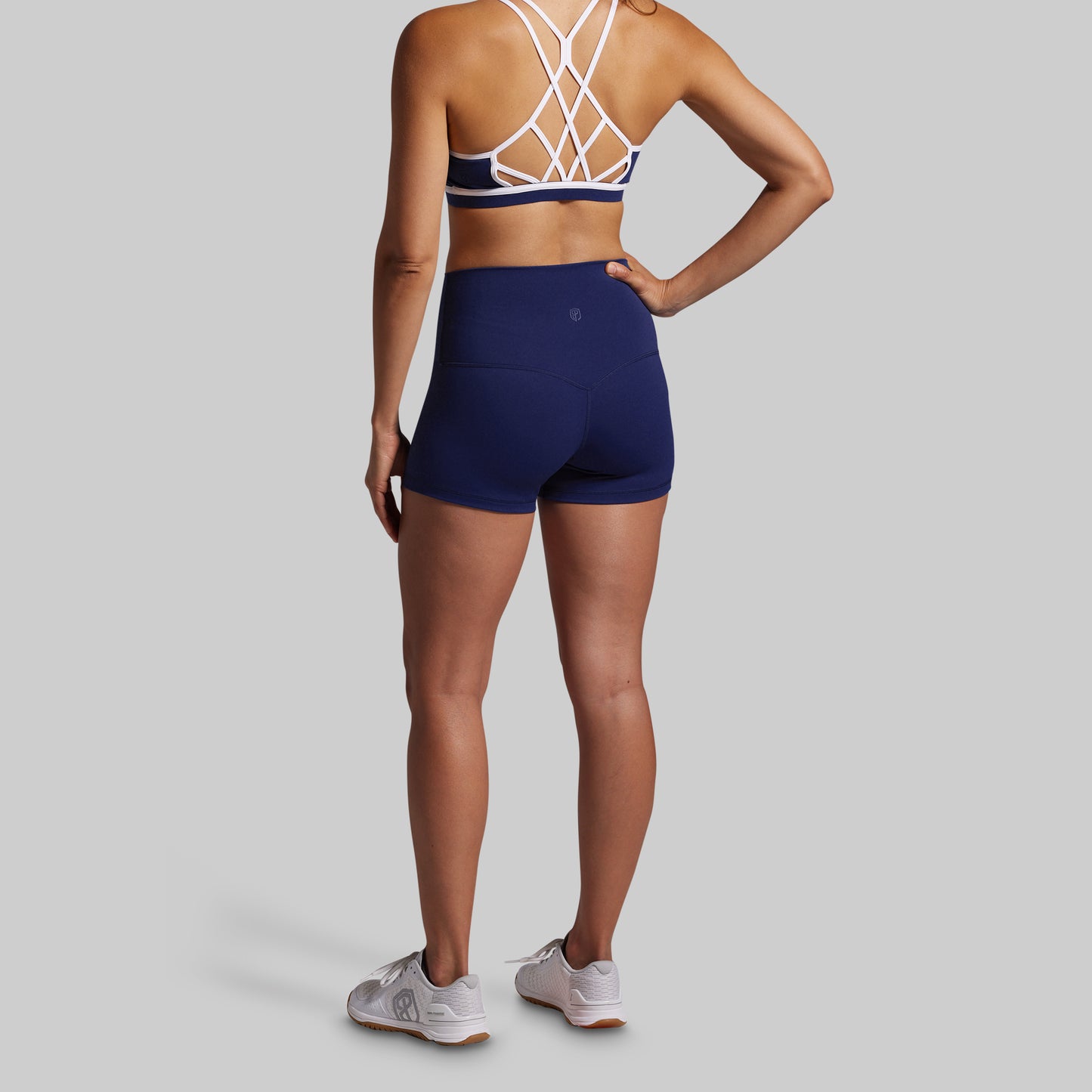 Person wearing a blue sports bra and shorts set on a gray background