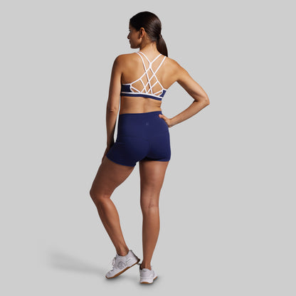 Woman wearing a sports bra and shorts set on a gray background