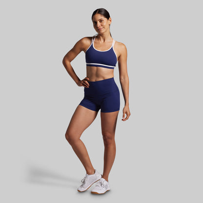 Woman wearing a blue sports bra and shorts set on a gray background